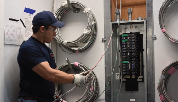 USIS employee in a room working on electrical equipment.

