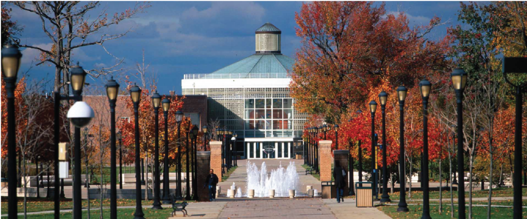 Scenic view of state university’s New York campus with fountain, trees, and autumn leaves.

