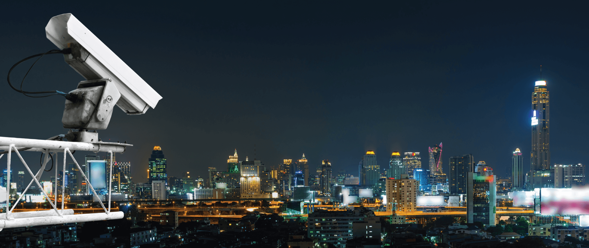 A camera overlooking night cityscape from a high rise building.